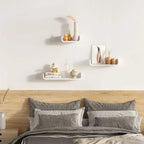 White floating wall shelves on a wall, holding small decor items.