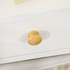 Close-up of a white drawer front with round brass-colored knob