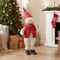 Christmas skiing Santa figure with red scarf and red cone hat, standing with ski poles