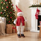 Christmas skiing Santa figure with red scarf and red cone hat, standing with ski poles