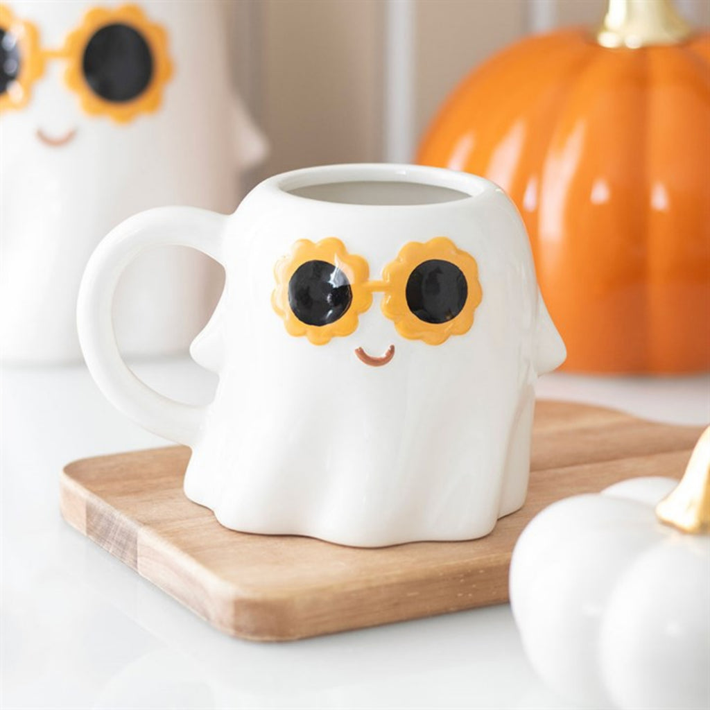 White mug with sunflower design on a wooden coaster with pumpkins in the background