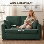 Dark green corduroy 2-seat sofa with two pillows, person reclining with book