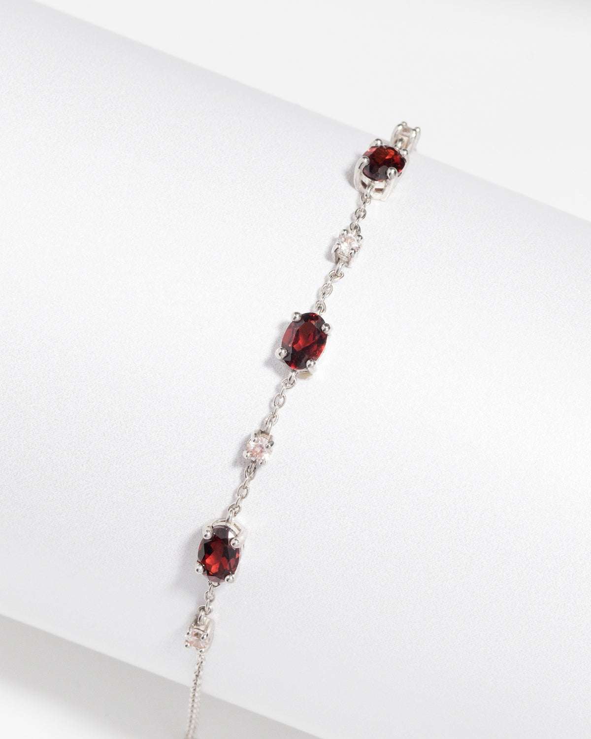 Sterling silver bracelet with three red oval gemstones and small clear stone accents