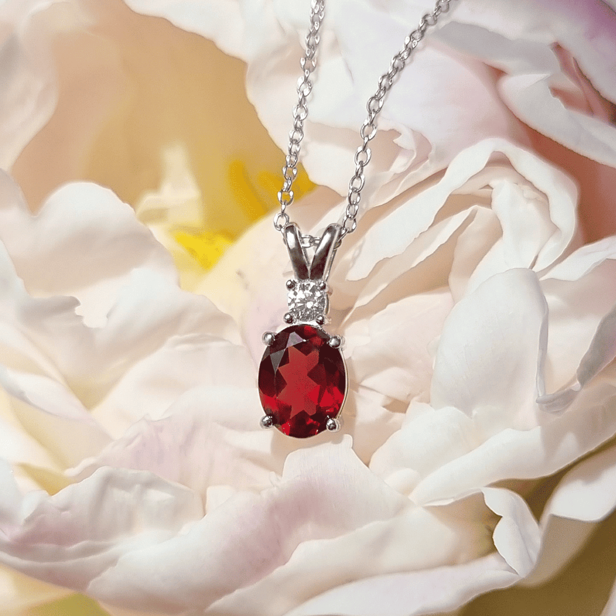 Sterling silver pendant necklace with red oval garnet centerpiece and small clear stones
