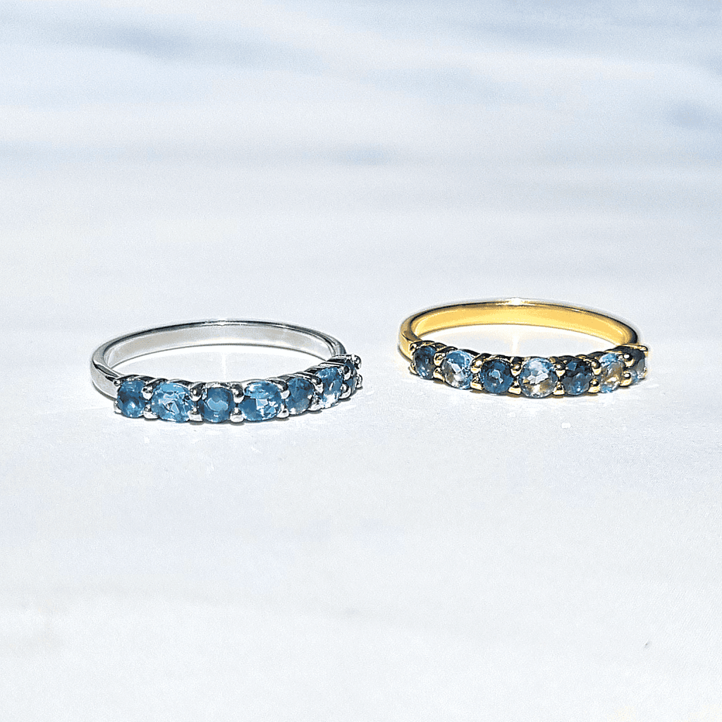 Blue gemstone half-eternity rings in silver and gold tones, side view (two rings)