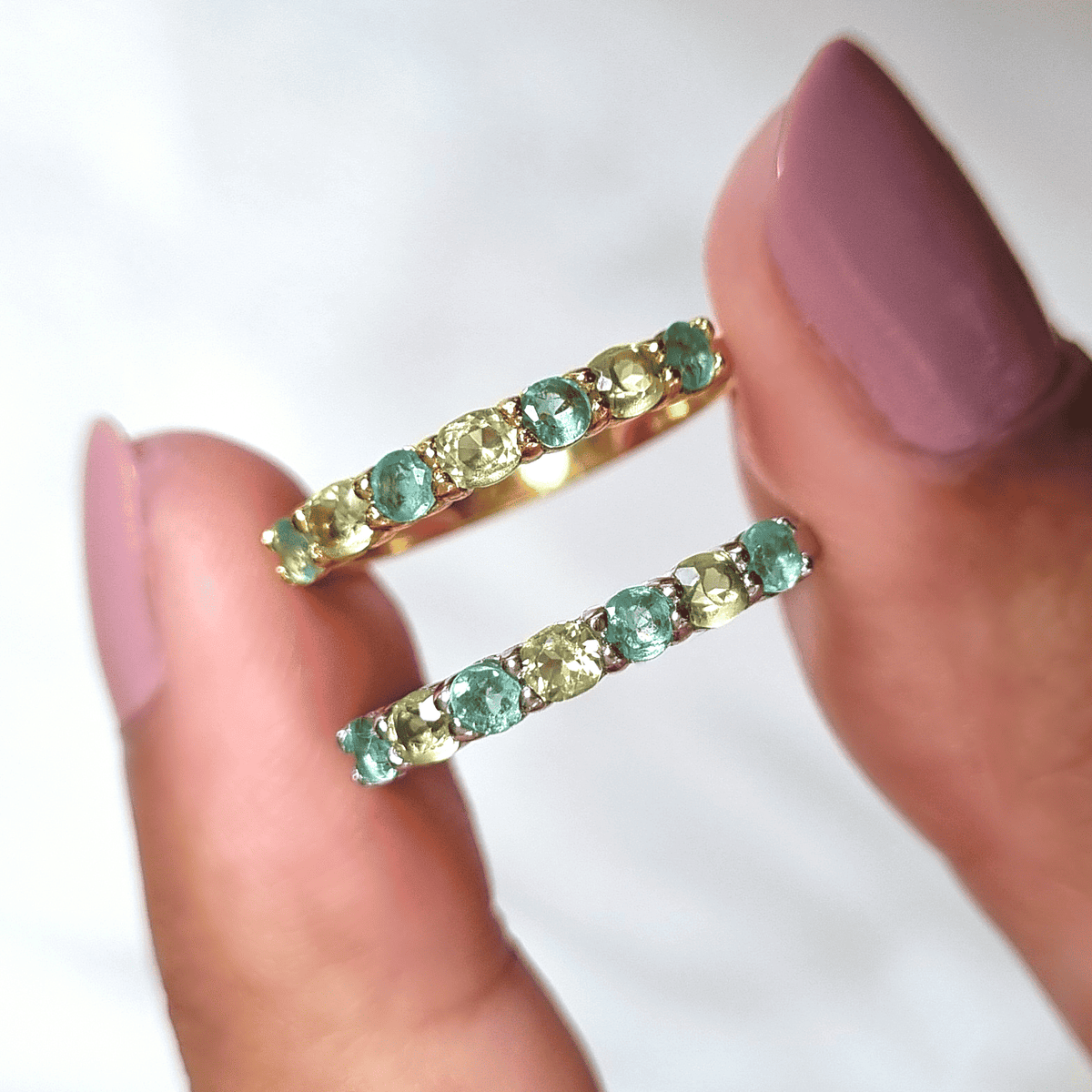 Pair of open rings with green and light-colored stones in gold-toned settings