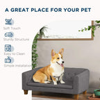 Grey dog sofa bed with tufted backrest and padded cushion; dog sitting on seat