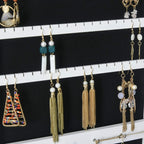 White jewelry armoire interior with tiered earring hooks and hanging necklaces