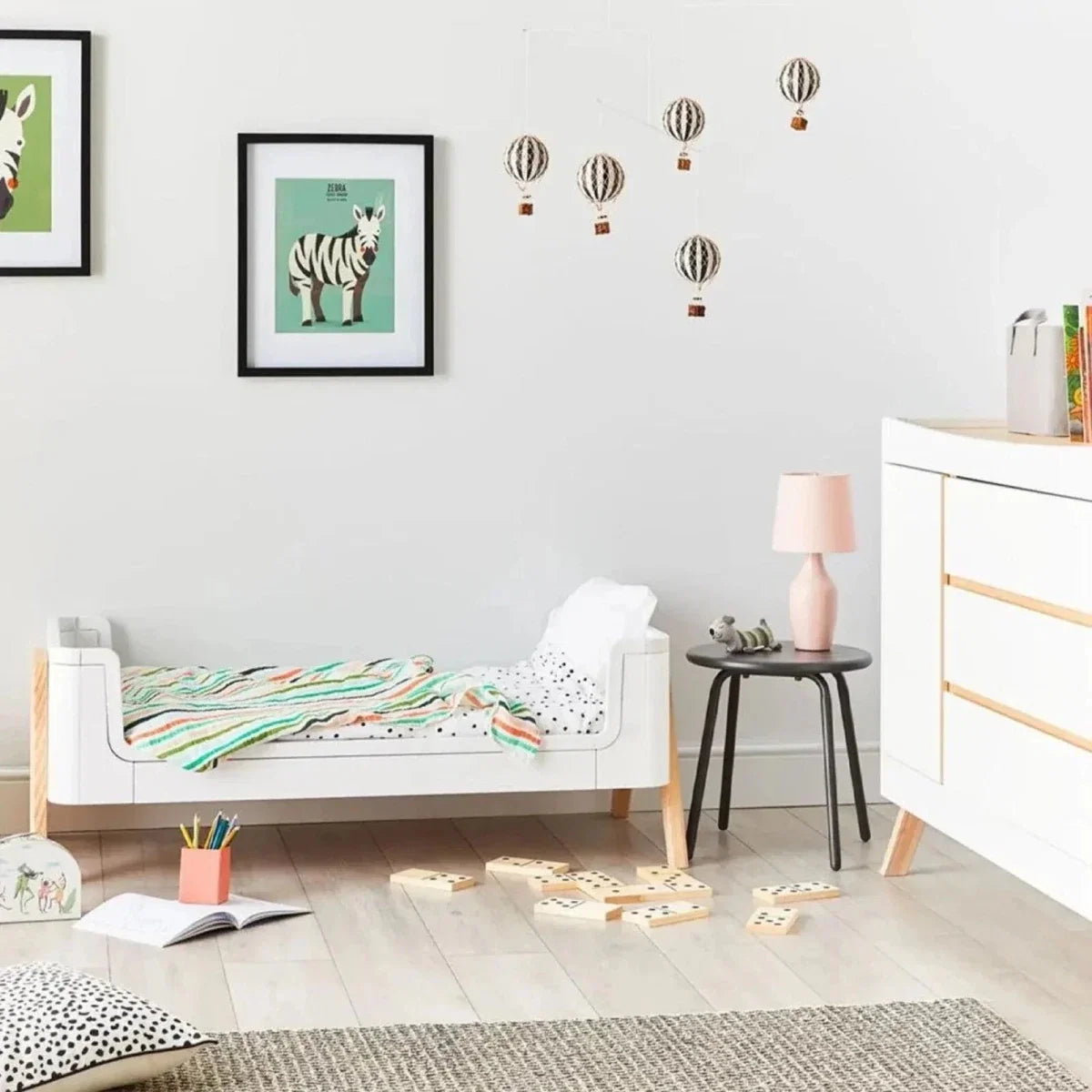 White junior bed extension with padded mattress, raised side rails and light wood legs