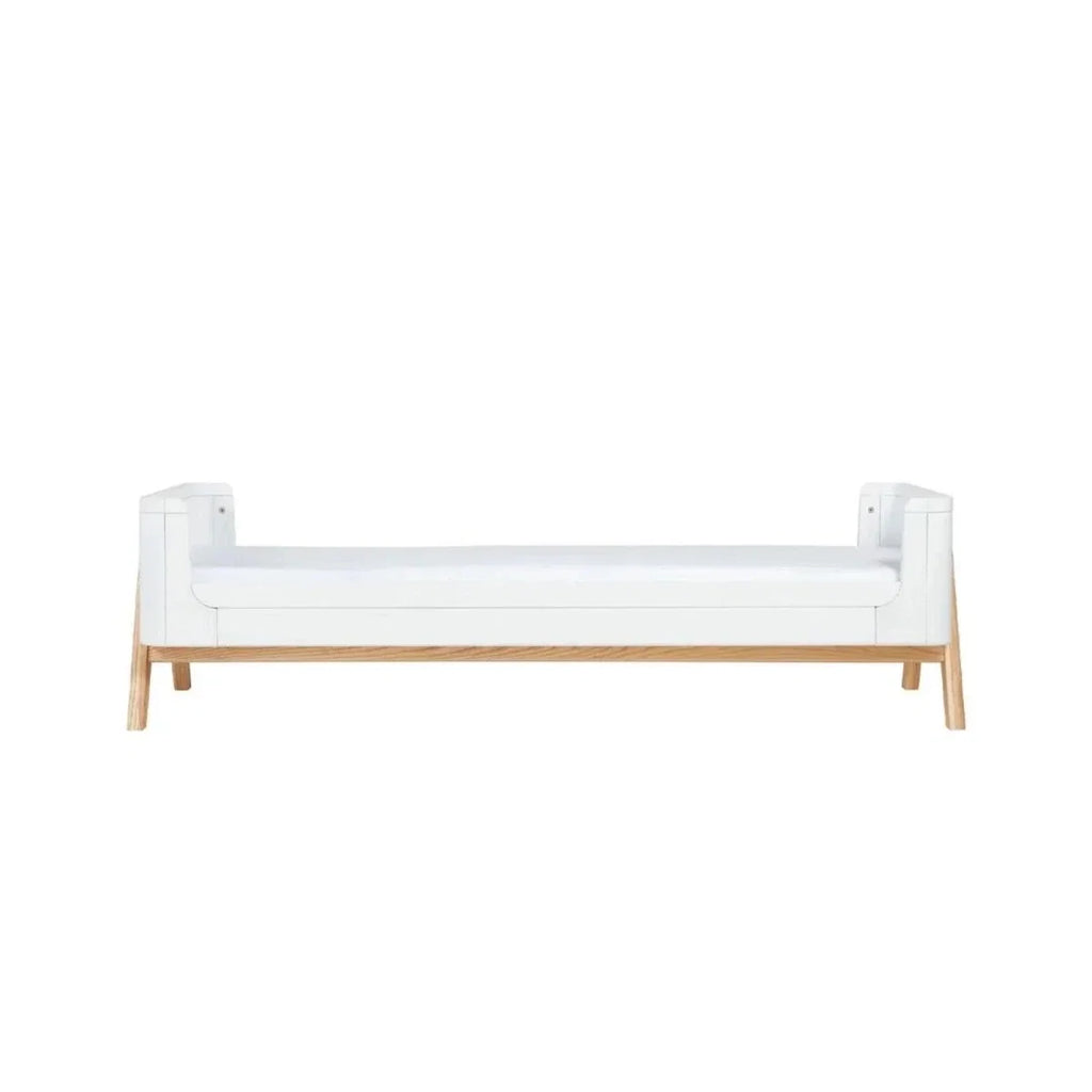 White junior bed extension with mattress, solid side panels and light wood legs