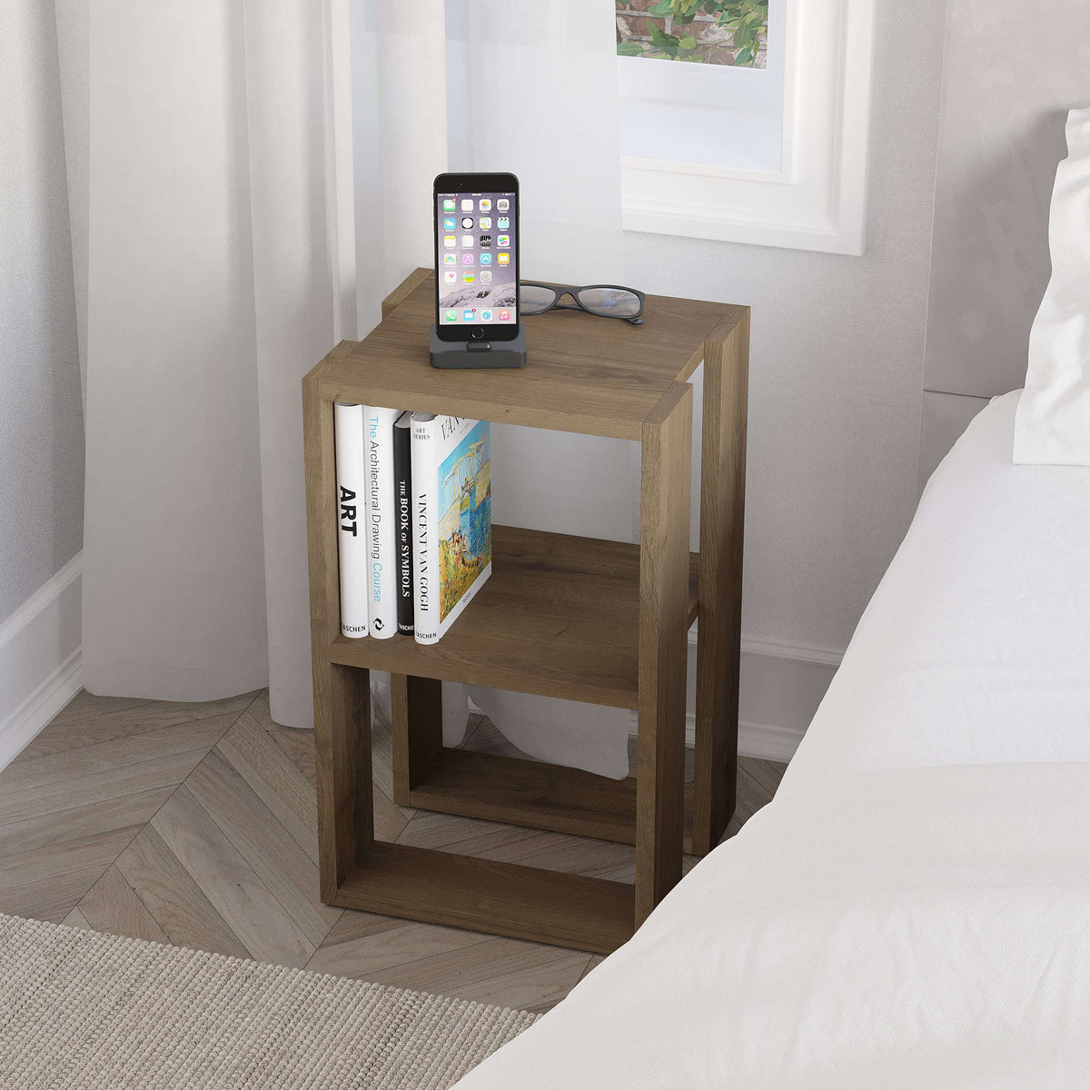 Wood bedside table with open shelves, tablet on top and books on the middle tier