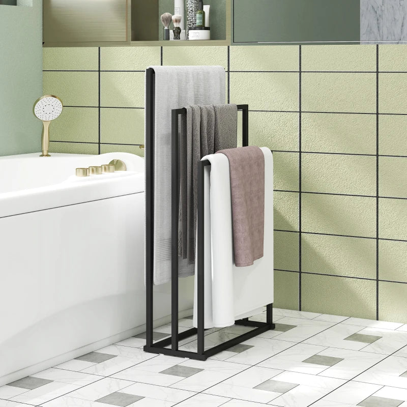 Black freestanding towel rack with three bars holding white and gray towels.