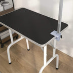 Dog grooming table with black rubber top, white frame, and corner support legs