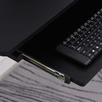 Black sliding keyboard tray pulled out from under the desk with a compact keyboard.
