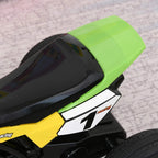 Close-up of green seat and yellow side panel on kids ride-on motorcycle trike with number "1".