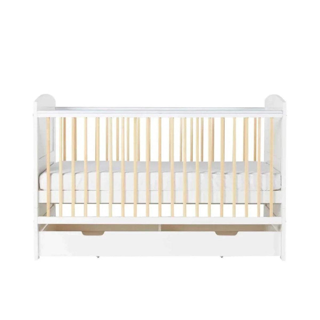 Front view of white cot bed with light wood slats and two under-drawer panels
