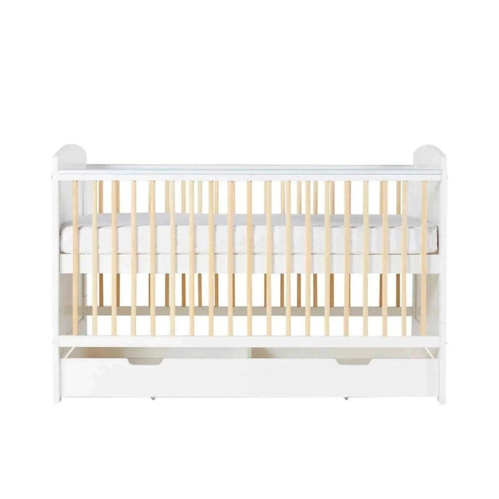 White cot bed front view with light wood slats and under-drawer storage