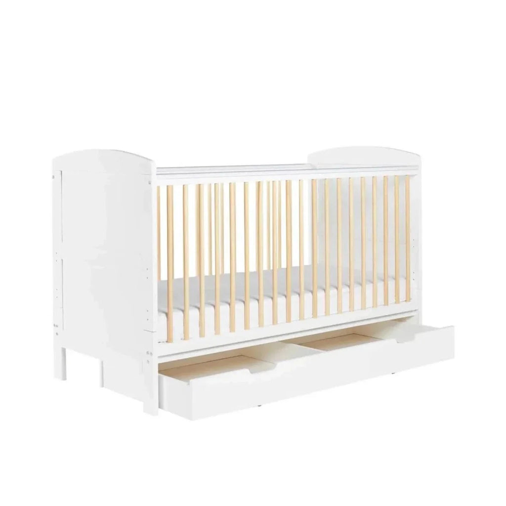 White cot bed end view with natural wood slat panel and under-drawer base