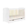 Scandi cot bed with white frame, light wood slats, and under-drawer storage