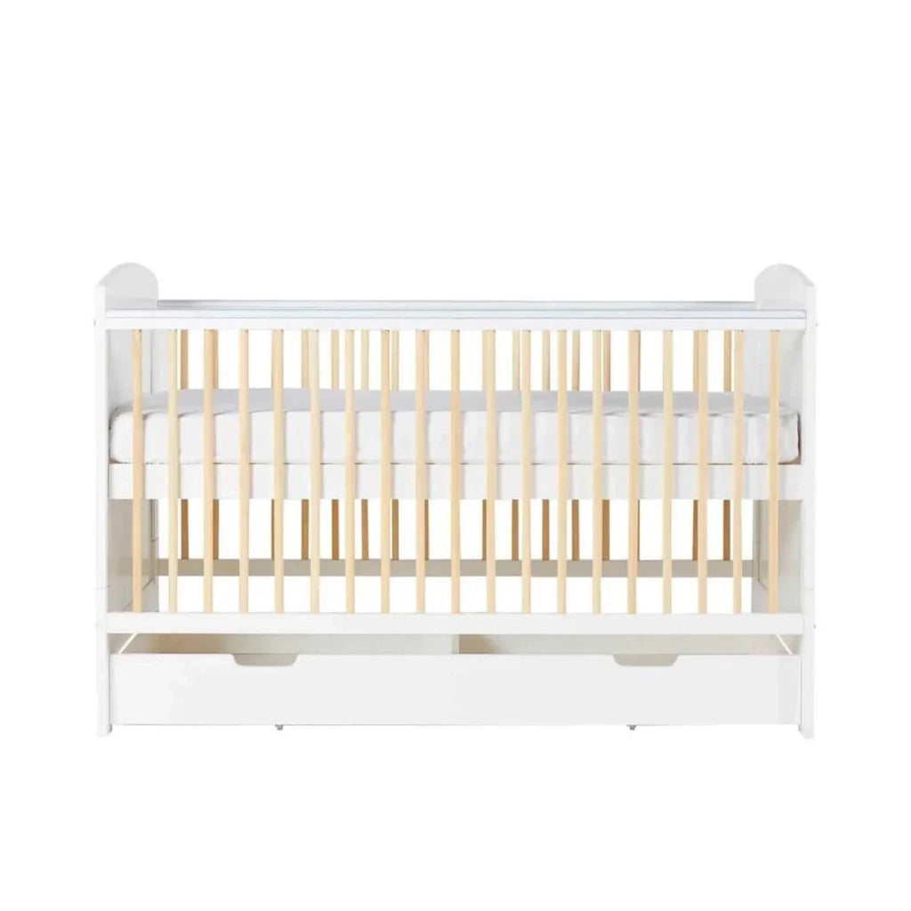 White cot bed with wooden slats and under-drawer storage drawer pulls, front view
