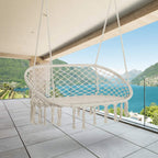 Cream hanging macrame hammock chair with oval net seat and long fringe tassels