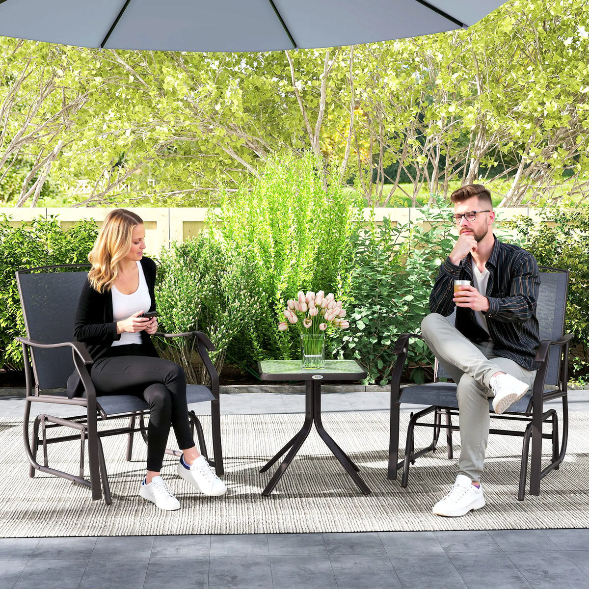 Two grey textilene rocking chairs with a glass-top table between them