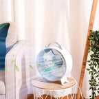 White portable desk fan with front safety grille on a small table