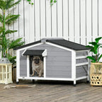 Grey wooden dog kennel with black roof mat and front door opening, with dog inside