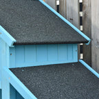 Blue wooden log storage shed with black asphalt roof panels and overhang