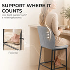 Grey velvet bar stool with curved backrest and footrest, black metal base