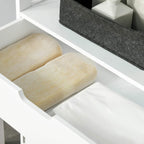 White cabinet drawer interior with folded light-yellow and white towels on a shelf