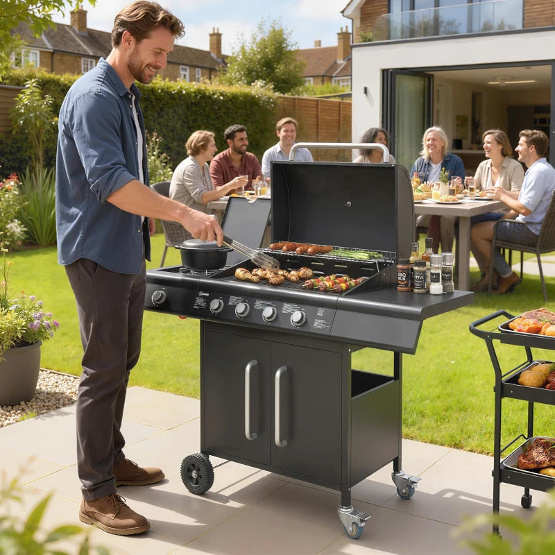 Black gas grill with open lid and food cooking on grates, storage doors visible