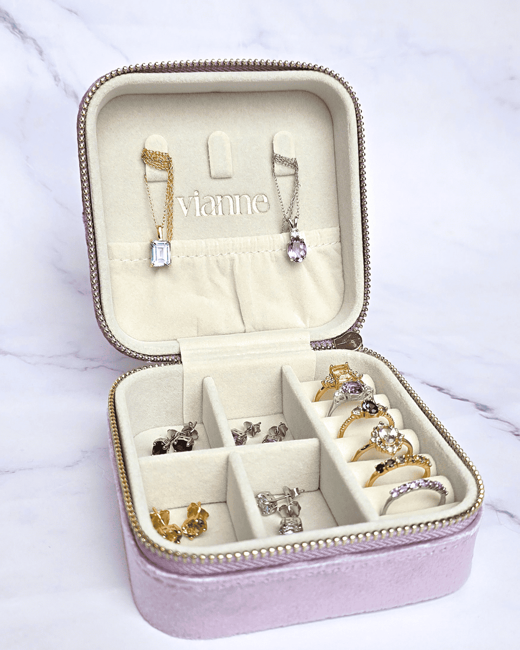 Lavender open jewelry travel case with ring slots and necklace hooks under zip lid.