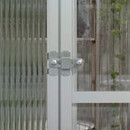 White aluminium frame greenhouse close-up of door latch and hinge on clear panel