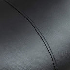 Close-up of black faux leather saddle stool seat with visible seam stitching