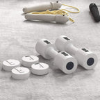 White adjustable dumbbells with removable discs and spare handle pieces on a tray