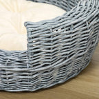 Close-up of grey wicker pet bed corner with beige cushion edge