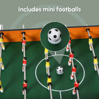 Foosball table with mini soccer balls on green pitch and player rod handles