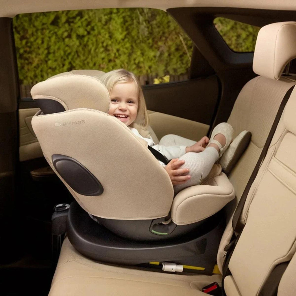 Child in grey car seat with headrest, harness, and padded side supports in vehicle