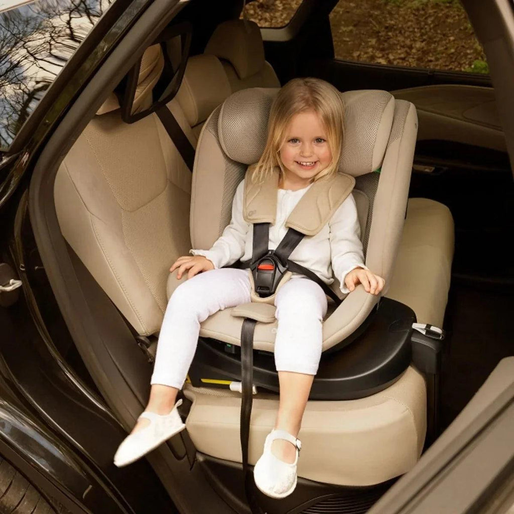 Grey child car seat with harness and headrest, front view in car.