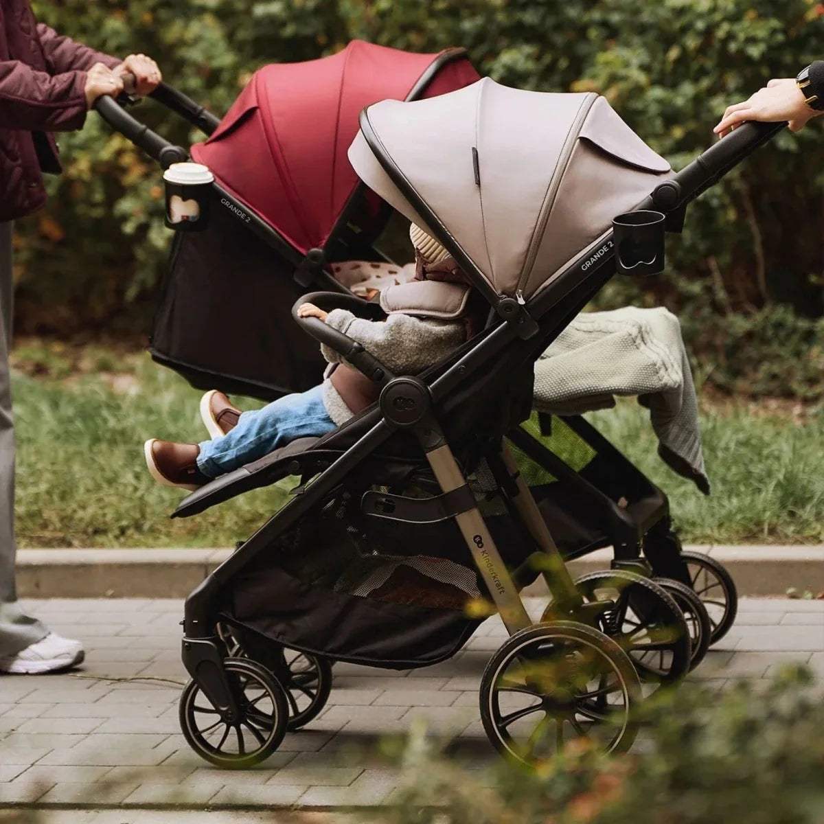 2-seat stroller with dark ruby canopy and beige seat, children riding, outdoors