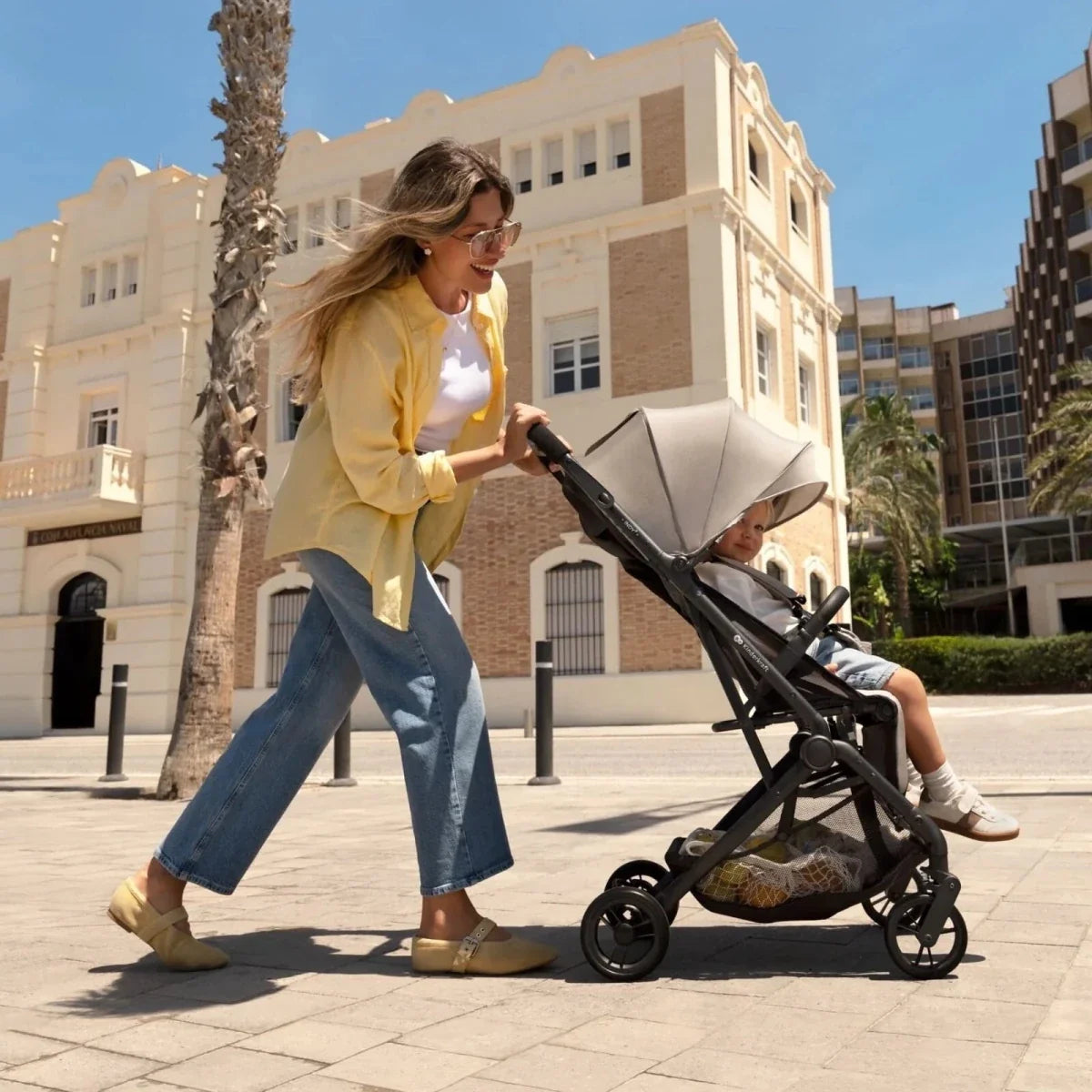 Kinderkraft Indy 3 stroller in misty beige with black frame, being pushed outdoors