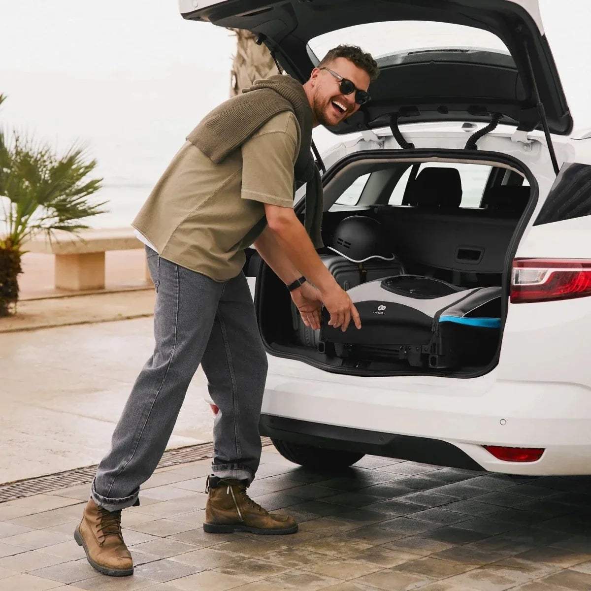 3-in-1 stroller with teal accents in the open trunk, ready to fold and load.