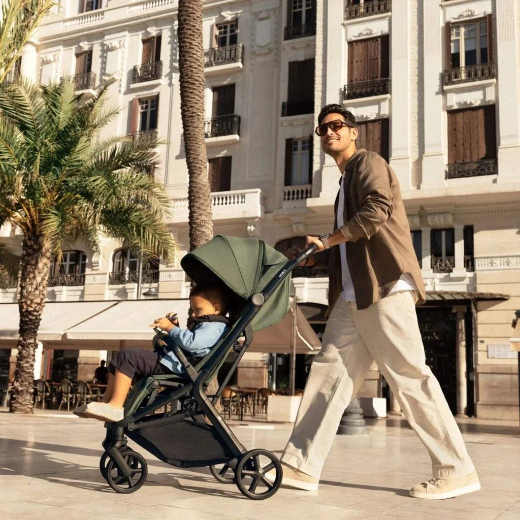 Compact stroller in dark green with canopy and reclining seat, side view
