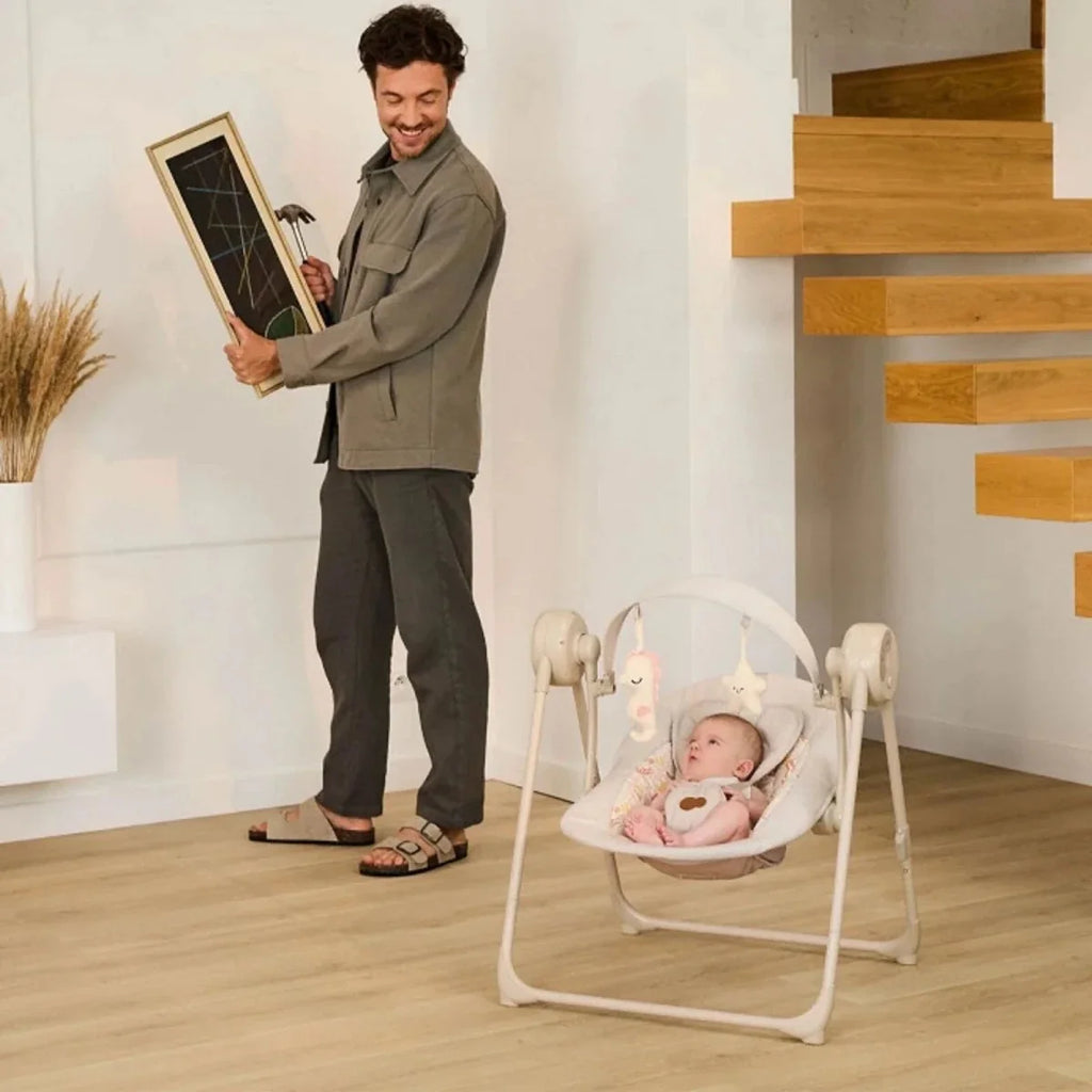Kinderkraft beige electric baby rocker bouncer with baby seated in the hammock-style seat