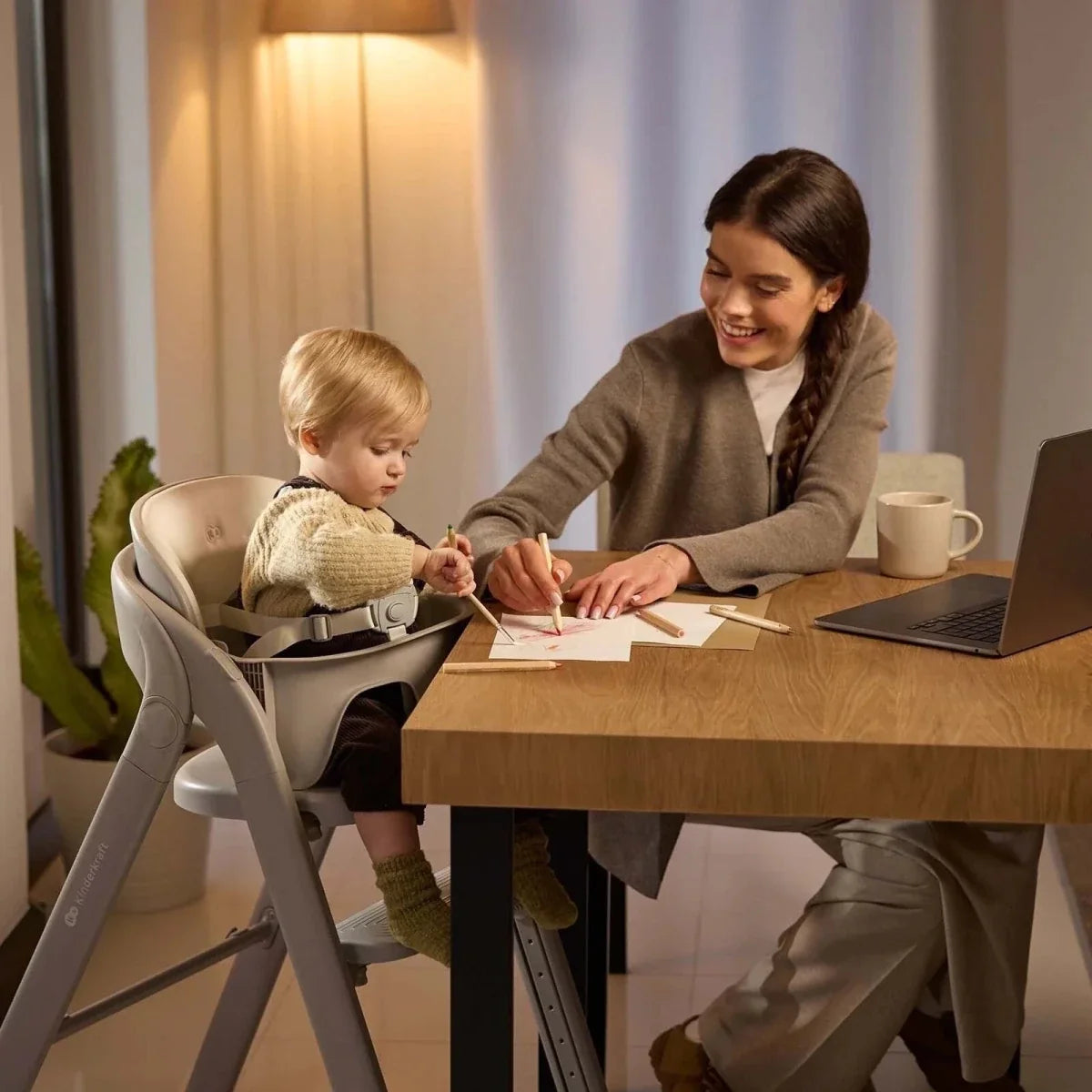 Beige 3-in-1 high chair used at a table with a child seated inside