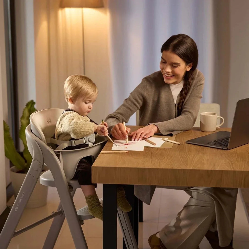 Grey high chair with cushioned seat and tray in use near table