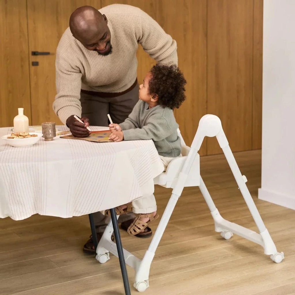 White-framed 3-in-1 high chair with padded seat and tray in family dining setting