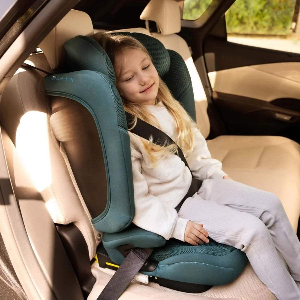 Child in car seat with headrest, padded side wings, and harness routing