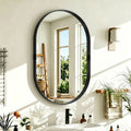 Black oval wall mirror mounted on wall with sleek rounded frame